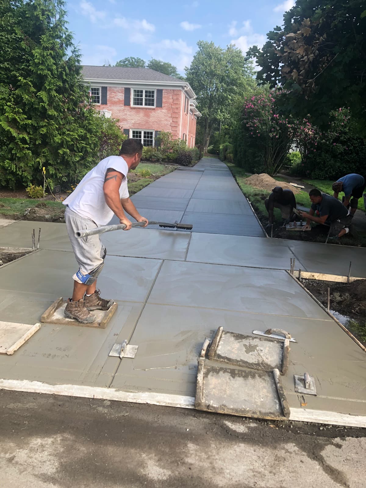 Crew finishing a freshly poured concrete driveway